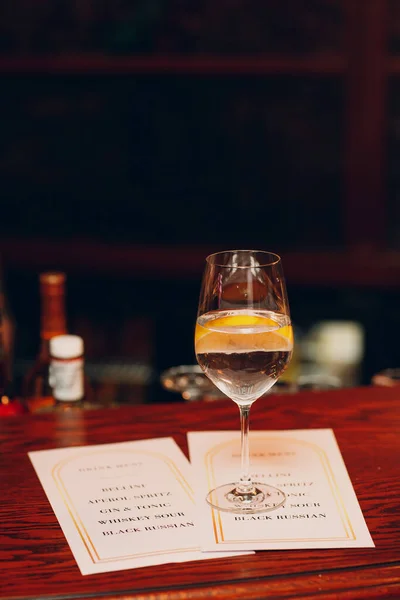 Cocktail com limão em vidro na mesa de bar com menu — Fotografia de Stock