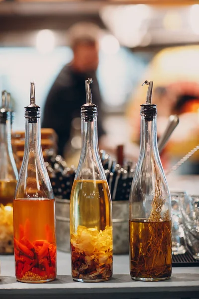 Aceite de oliva en botella con ajo, pimiento rojo y romero sobre mesa en pizzería — Foto de Stock