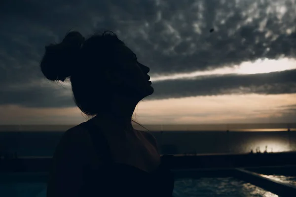 Silhueta do retrato de mulher que está contra o céu nublado — Fotografia de Stock