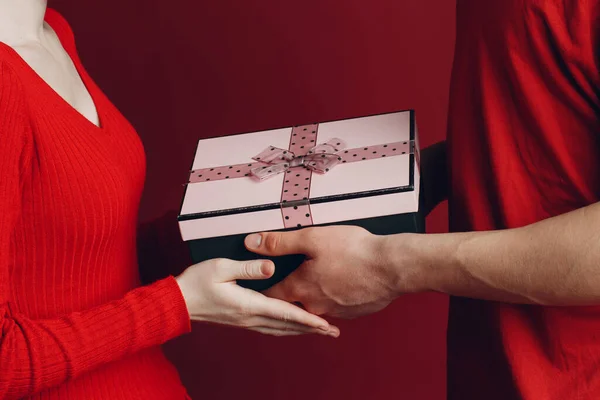 Valentinstagsgeschenk. Glückliches junges Paar mit Valentinstagsgeschenk isoliert auf rotem Hintergrund. — Stockfoto