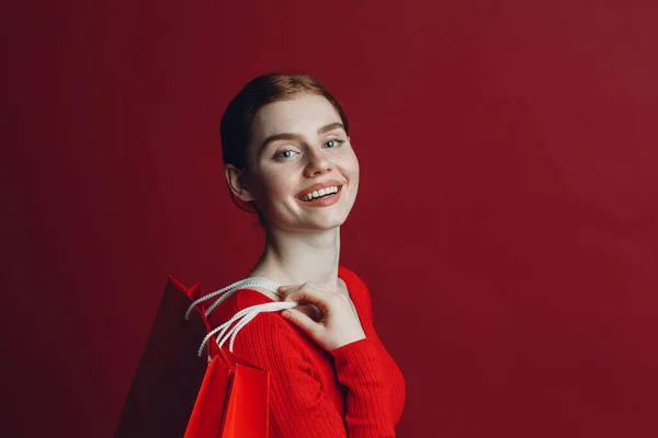 Wanita cantik tersenyum potret dengan kertas tas belanja merah. Jumat hitam dan konsep penjualan. — Stok Foto