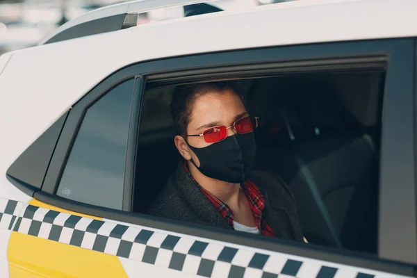 Man passenger in protective face medical mask in the taxi car during an epidemic quarantine city. Health protection, safety and pandemic Covid-19 concept. — Stock Photo, Image