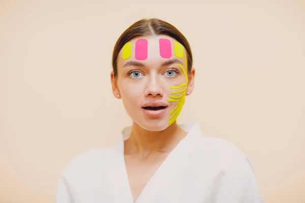 Beautiful woman applying tape lifting treatment on face — Stock Photo, Image