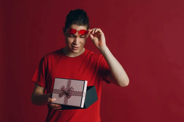 Pria tampan dengan kotak hadiah dengan latar belakang merah — Stok Foto