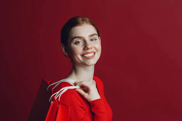 Wanita cantik tersenyum potret dengan kertas tas belanja merah. Jumat hitam dan konsep penjualan. — Stok Foto