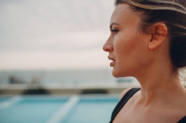 Bulutlu gökyüzünde duran genç kadın portresi