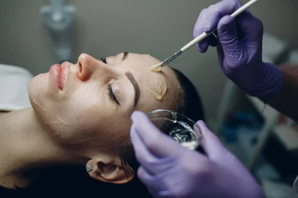 Esteticista aplicando com escova contato gel de hidrogenação fria no rosto da mulher para procedimentos de hardware no spa de beleza — Fotografia de Stock