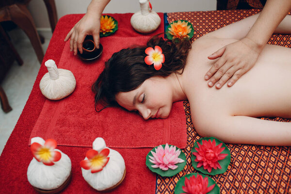 Thai man making classical thai massage procedure to young woman at beauty spa