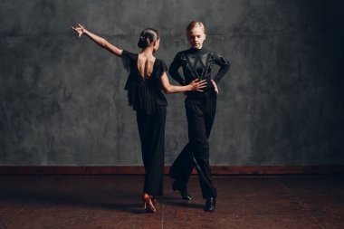 Siyah kostümlü çift balo salonunda rumba dansı yapıyor..