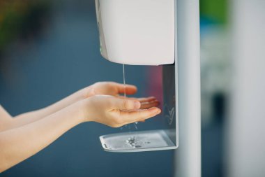 Çocuk çocuk elinde otomatik alkol jeli spreyi ile antiseptik dezenfektan sıkarak Coronavirüs COVID-19 pandemisi sonrası yeni normal bir hayat sürüyor.