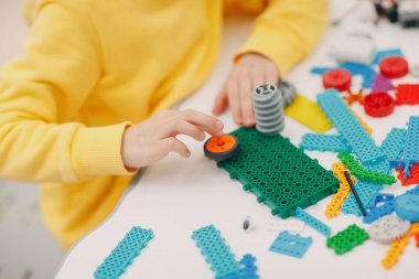 Gülümseyen çocuk inşaatçısı teknik oyuncakları kontrol ediyor. Çocuklar, robot inşaatçısı robot monte ediyor..