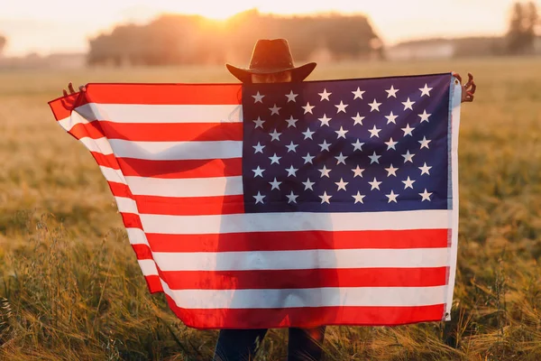 Mujer agricultora en el campo agrícola con bandera americana al atardecer — Foto de Stock