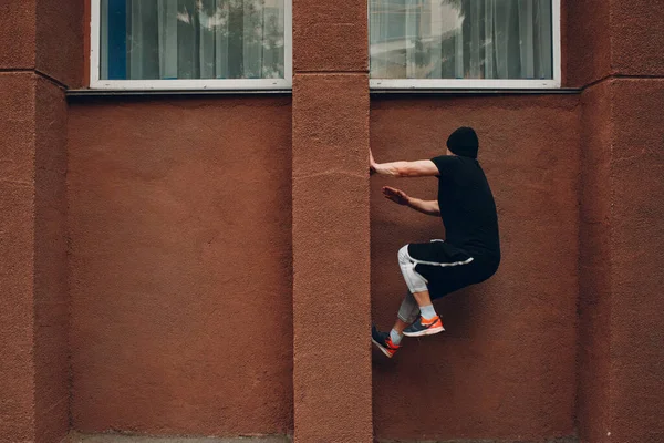 Young sporty guy doing parkour at the city street.