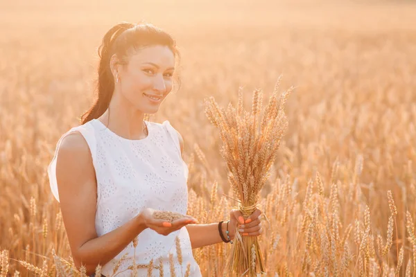 Donna sorridente bruna tenuta in mano palma covone di spighe di grano al campo agricolo — Foto Stock