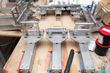 Giyim fabrikasında seri ipek ekran baskı işlemi. Gerginleştirici Çerçeve, cam sileceği ve plastisol rengi