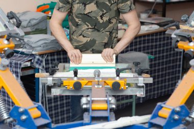 Giysi fabrikasında işçi baskısı resim uygulaması serisi ipek ekran baskı işlemi. Çerçeve, cam sileceği ve plastisol rengi