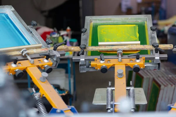 Carrousel Frame, squeegee en plastisol kleur verf Serigrafie zeefdruk proces in de kledingfabriek. — Stockfoto