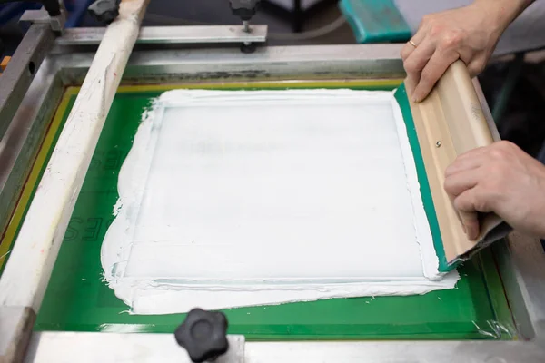 Serigrafie zeefdruk proces in de kledingfabriek. Frame, squeegee en plastisol verven — Stockfoto