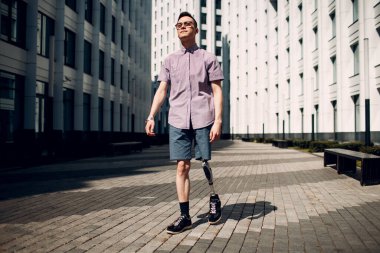 Ayakları protezle yürüyen engelli genç adam.