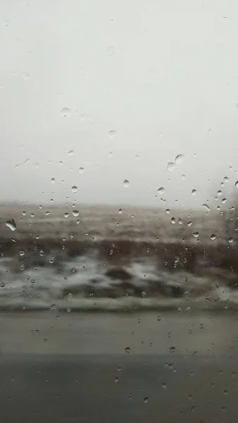 Краплі дощової води на віконному склі за туманною дорогою — стокове фото
