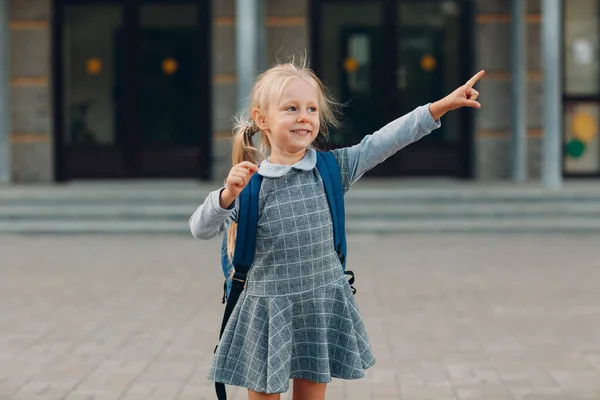 Söt liten flicka med ryggsäck som går tillbaka till skolan och pekar långt hennes finger — Stockfoto
