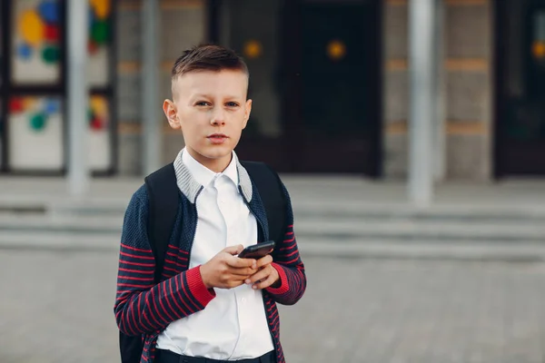 Estudante adolescente menino com telefone celular em pé na escola no fundo — Fotografia de Stock