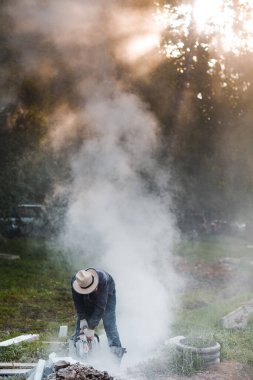 İşçi ustası kaldırımı dairesel testereyle keserken kaldırımı onarıyor.