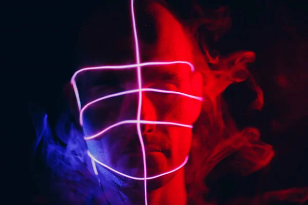 Retrato del hombre con líneas de tubo de neón brillante con humo en su cara en la oscuridad. Concepto cyberpunk y realidad virtual. — Foto de Stock