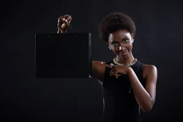 Африканская американка держит чёрные сумки для покупок. Продажи и скидки на рынке и концепция "черной пятницы". — стоковое фото