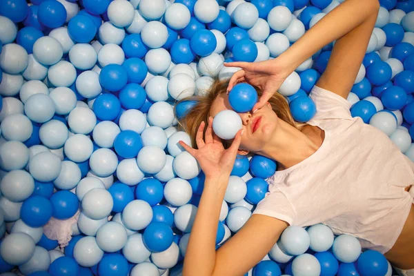 Young woman playing with white and blue balls in a dry pool. — Stok Foto