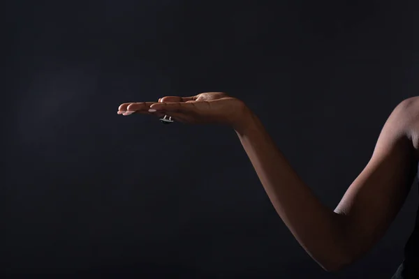 Pusta kobieca ręka afrykańskiej amerykanki trzymającej na czarnym tle — Zdjęcie stockowe