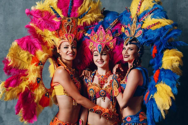 Tres mujeres en traje de carnaval de samba brasileña con plumaje de plumas de colores —  Fotos de Stock