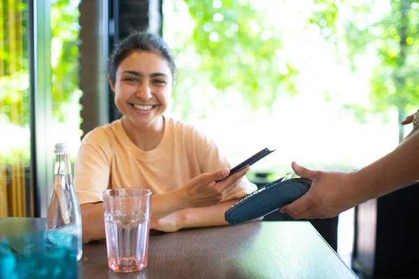 Индианка платить с мобильного телефона NFC бесконтактный платежный терминал в кафе-баре. — стоковое фото