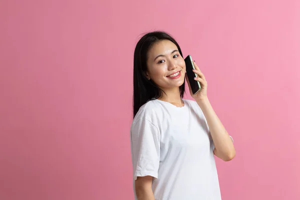 Sorrindo mulher asiática falando telefone celular de pé no fundo rosa. — Fotografia de Stock