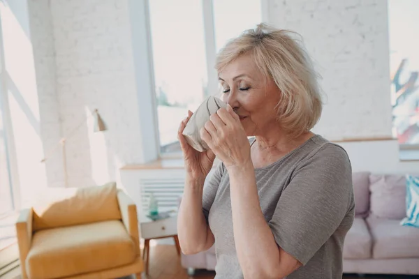 Oudere Kaukasische oude vrouw geniet 's middags thee thuis. — Stockfoto