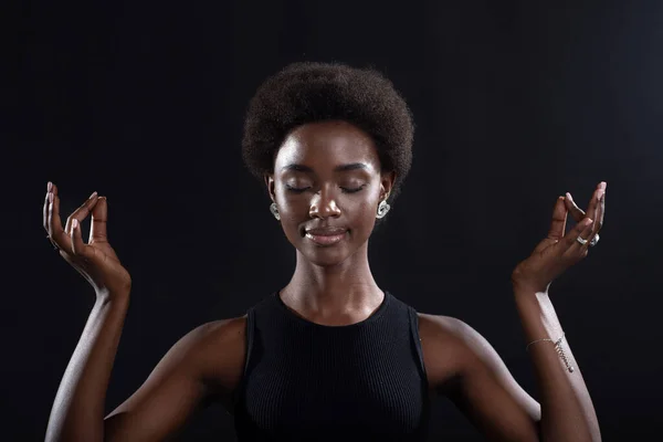 Studio ritratto di modello afro-americano femminile che mostra zen o gesto segno ok. Donna che medita su sfondo nero. — Foto Stock