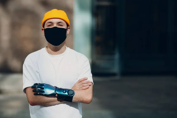 Junger behinderter Mann mit künstlicher Handprothese und medizinischer Schutzmaske. — Stockfoto