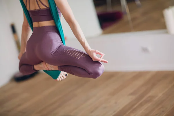 Woman doing aerial yoga in studio. Female practicing air yoga in hammock