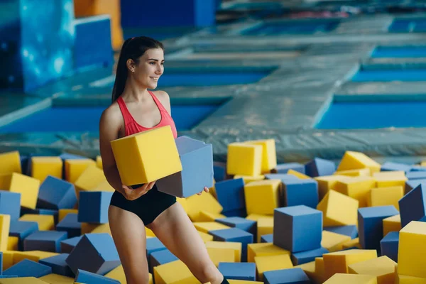 Giovane e bella donna gioca in piscina asciutta con cubi — Foto Stock
