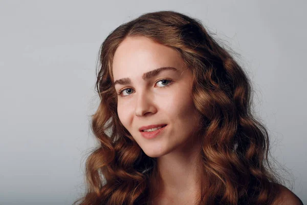 Портрет женщины с волнистыми волосами на сером фоне — стоковое фото
