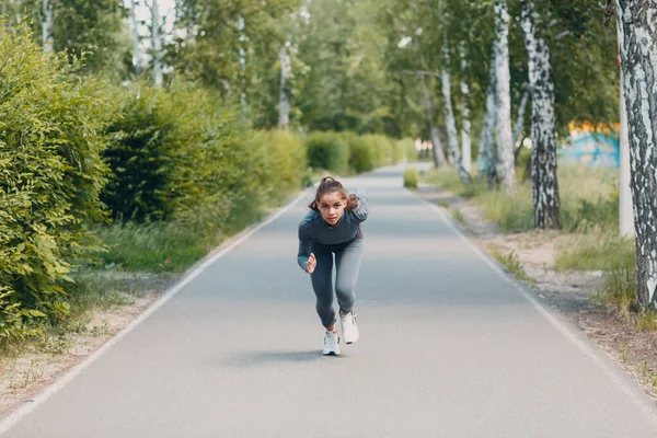 Mujer atlética en pista empezando a correr. Chica trotando. —  Fotos de Stock