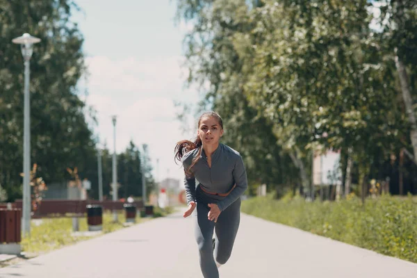 Şehir parkında koşan kız. Genç bayan koşucu dışarıda koşuyor.. — Stok fotoğraf