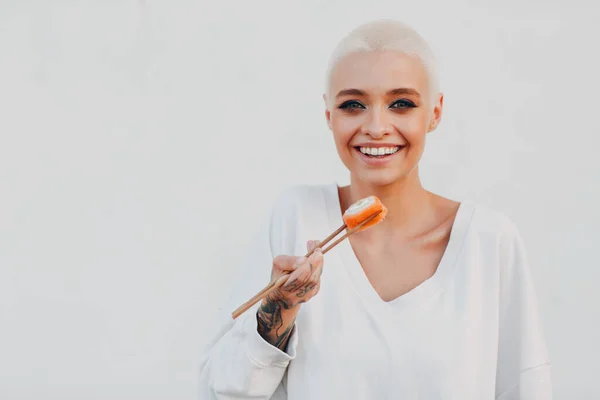 Wanita muda jutawan berambut pendek di luar ruangan tersenyum potret dengan sushi gulung. — Stok Foto