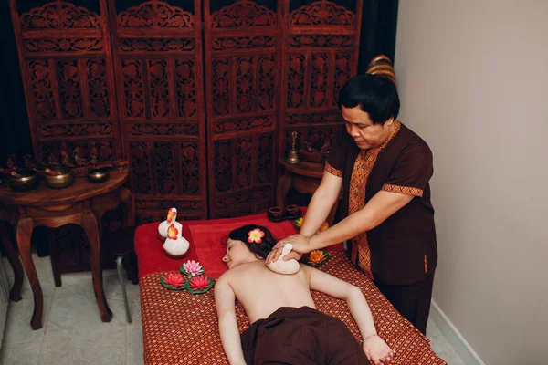 Thai man making classical thai massage procedure to young woman at beauty spa — Stock Photo, Image