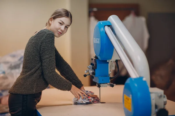 Penjahit muda cantik desainer pakaian memotong kain pada mesin — Stok Foto