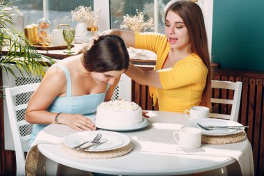 Genç kadın yüzünü kremalı pastaya daldırıyor. Mutlu yıllar..