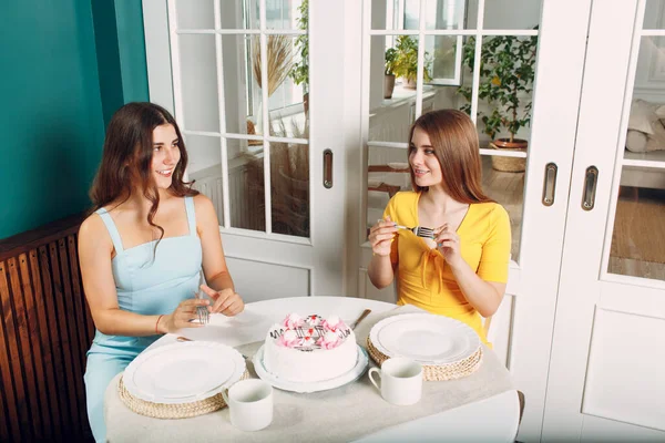 Perempuan bahagia teman-teman di rumah duduk dan tersenyum dengan kue ulang tahun putih — Stok Foto