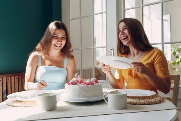 Perempuan bahagia teman-teman di rumah duduk dan tersenyum dengan kue ulang tahun putih — Stok Foto