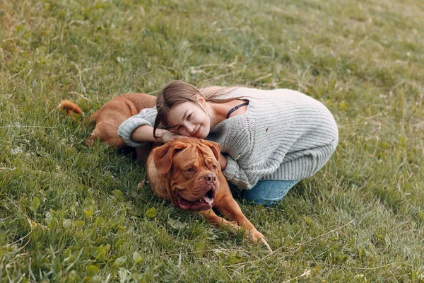 Dogue de Bordeaux nebo francouzský mastiff s mladou ženou na louce v parku — Stock fotografie