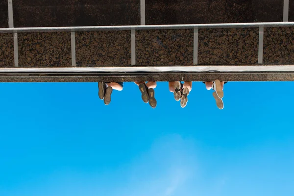Anak laki-laki kaki di sepatu tergantung dari jembatan terhadap langit biru — Stok Foto